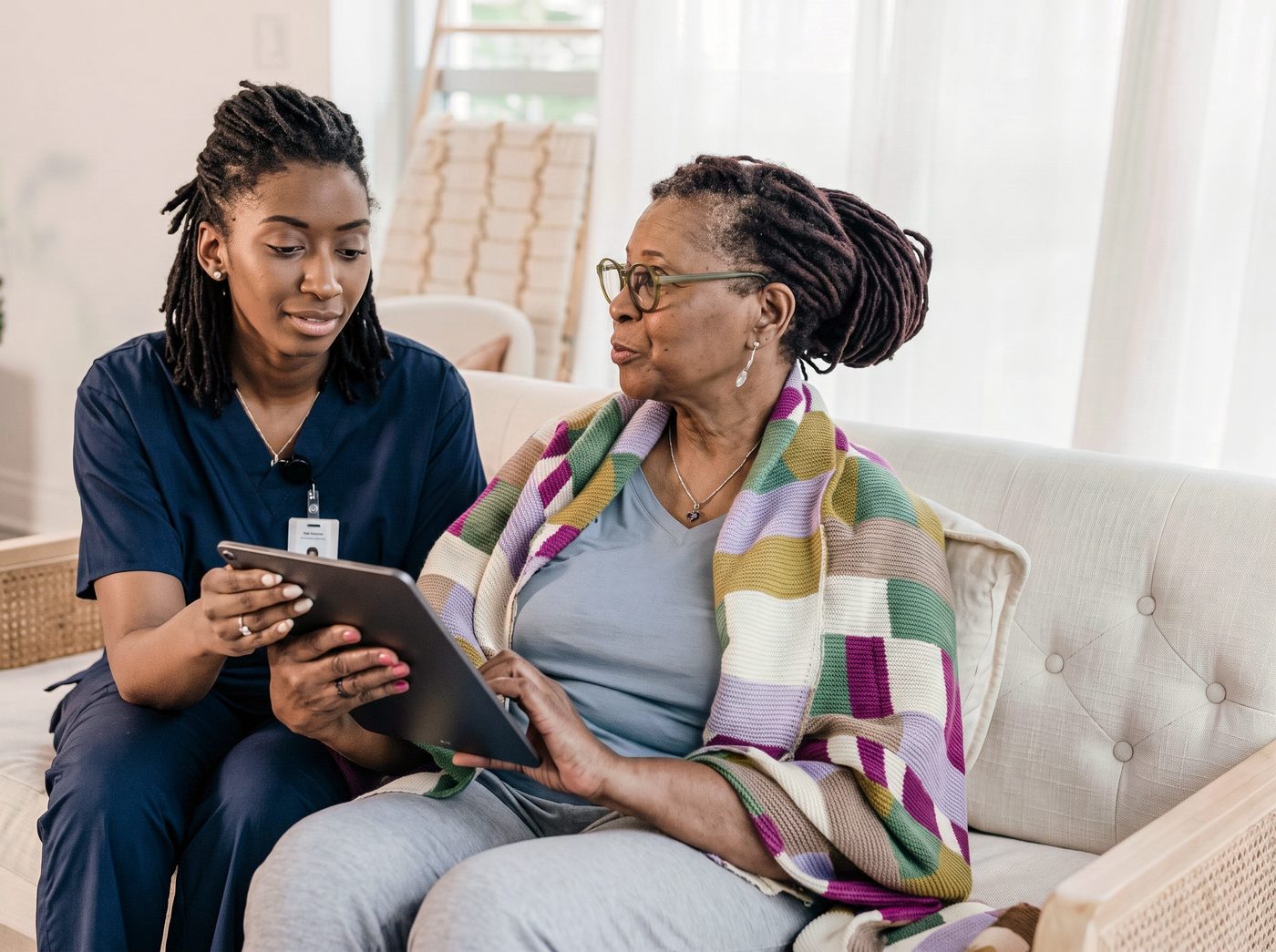 Caregiver sharing a tablet with a senior on the sofa