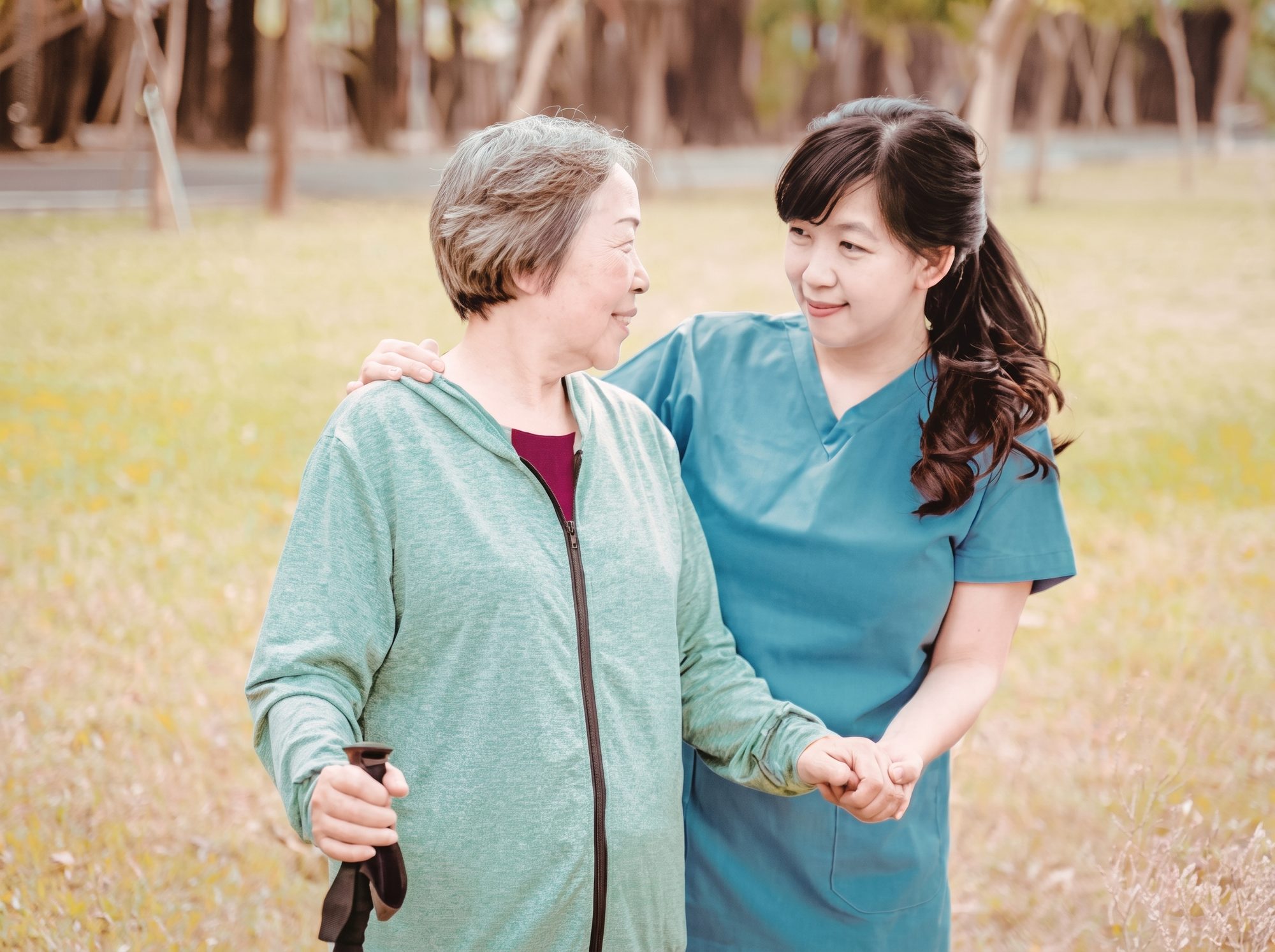 An ExcelCare caregiver walking arm in arm with a senior client outdoors