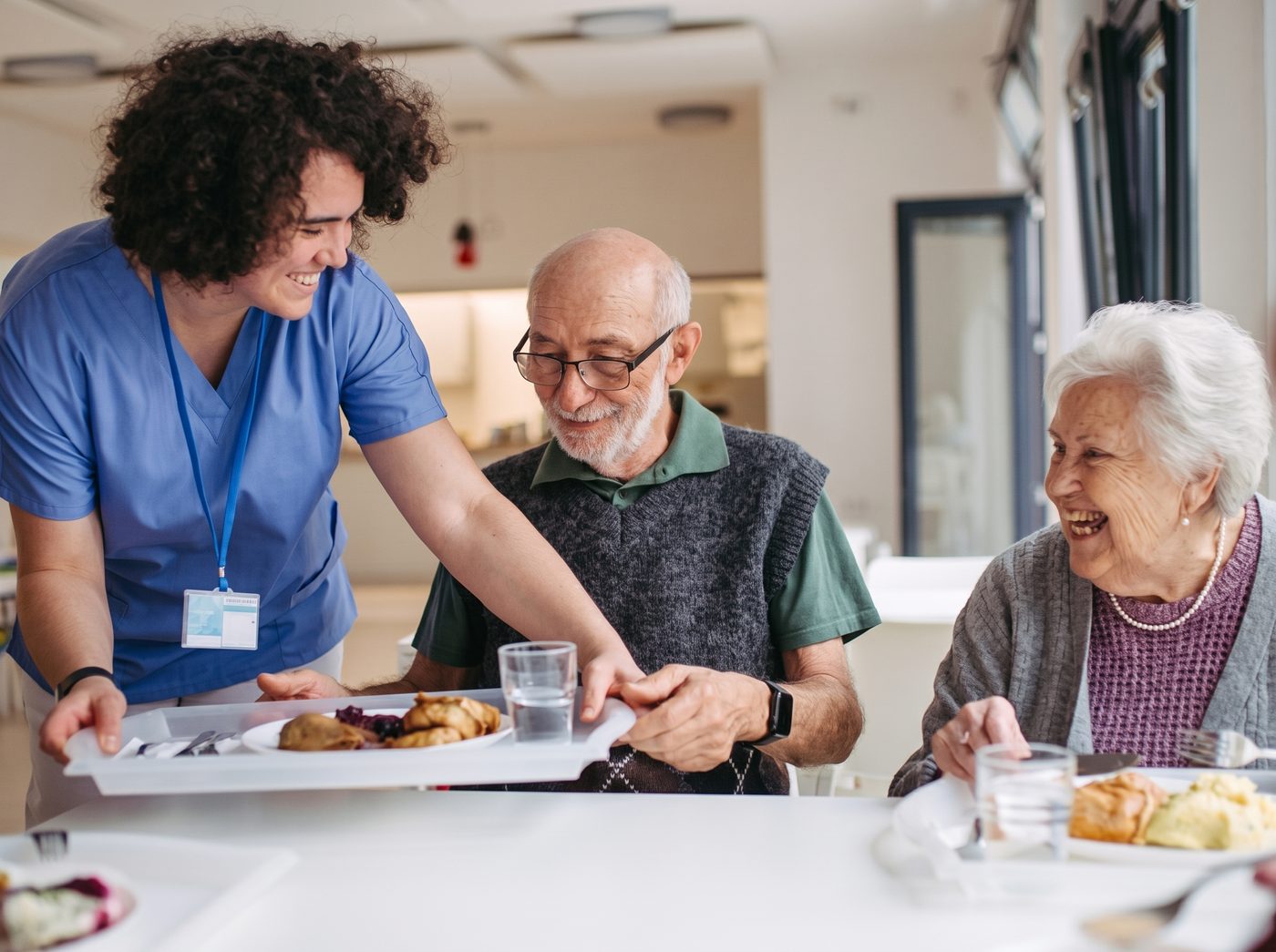 Caregiver serving a meal to seniors
