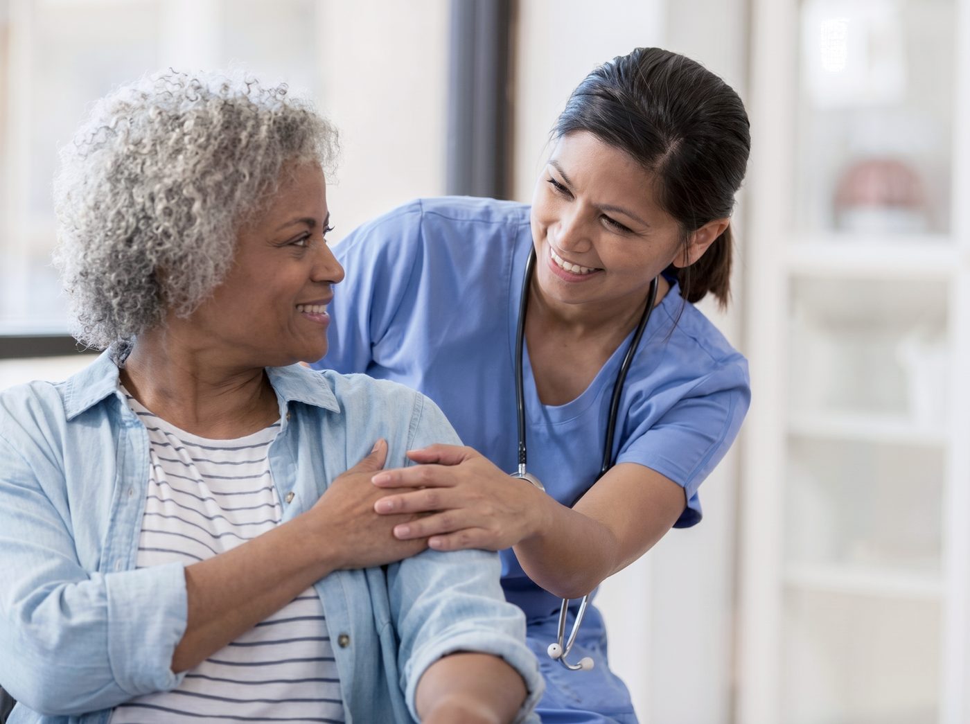 Caregiver with an arm around a smiling senior